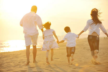 快乐的年轻一家在日落的海滩上玩得开心