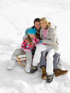 一家人坐在雪地里的雪橇上
