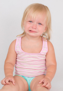 可爱不满意的女孩坐在白色的椅子上哭泣悲伤的小女孩戴着游泳护目镜坐