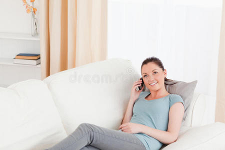可爱的女人躺在沙发上打电话