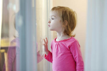 好奇的孩子望着窗外照片