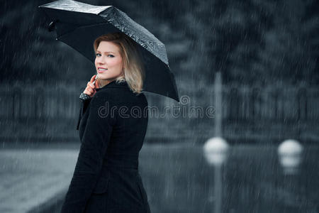 时尚女人带着雨伞在雨中行走