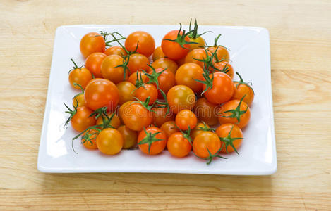 白色盘子里摆着橙色的樱桃西红柿