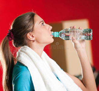 在健身房喝水的女人