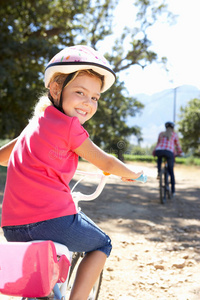 小女孩微笑着和妈妈骑自行车