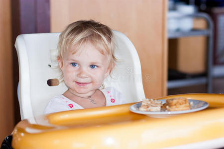 可爱的婴儿坐在椅子上吃蛋糕