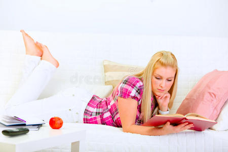 现代家庭主妇躺在沙发上看书图片
