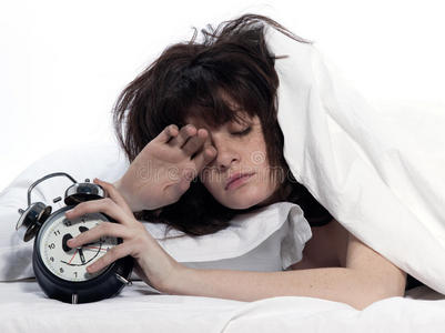 女人在床上醒来累得拿着闹钟