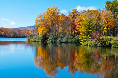 秋天的树叶倒映在湖面，蓝色的山脊上。