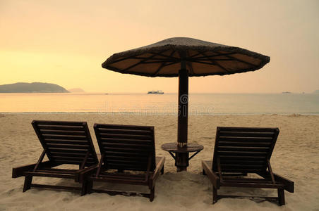 日出时海滩上的太阳椅和雨伞