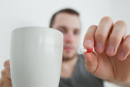 拿着药片和杯子的男人