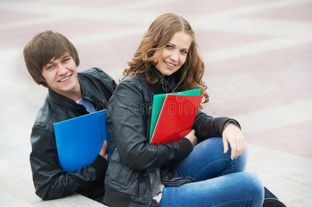 两个微笑着在户外学习的年轻学生