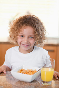 快乐女孩早餐吃麦片和橙汁