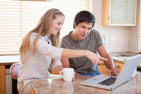 一对微笑的夫妇一边喝咖啡一边使用笔记本电脑
