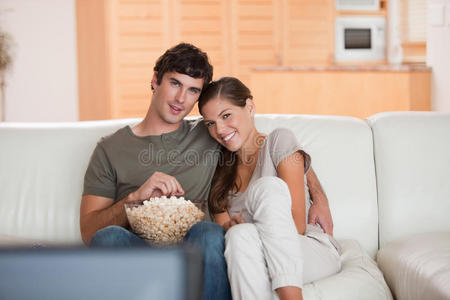 夫妻俩拿着一碗爆米花在沙发上看电影