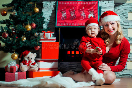 妈妈和宝宝戴着圣诞帽在壁炉旁