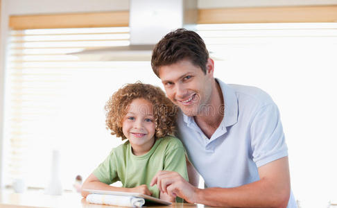微笑的男孩和他父亲用平板电脑