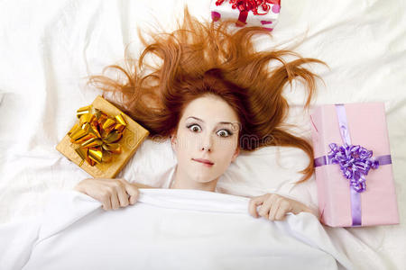 惊讶的红发女孩在床上拿着礼物。
