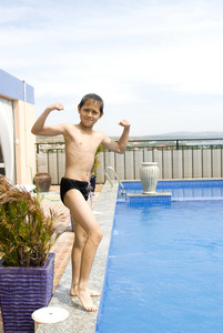 男孩在游泳池旁展示肌肉