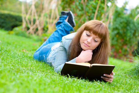 躺在草地上看书的年轻女子