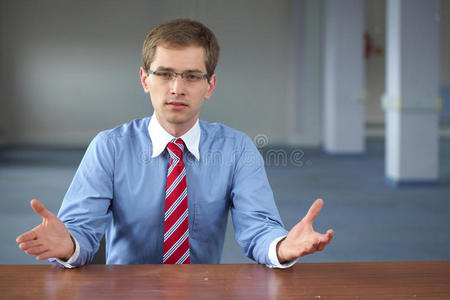 穿着蓝色衬衫的年轻商人坐在办公桌旁