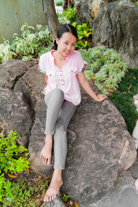 公园岩石上微笑的亚洲女人