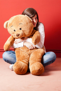 坐在地板上拥抱泰迪熊的年轻女子