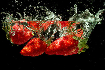 草莓溅入水中在水中的草莓闪屏黑色背景水中的草莓亚洲妇女在游泳池