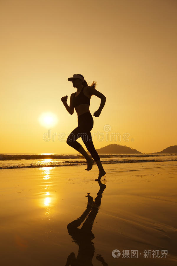 海滩跑步女孩的剪影,在海浪中跳跃沙滩跑步沿着海岸奔跑的人女运动员