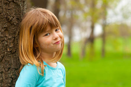 微笑害羞的小女孩靠在树上