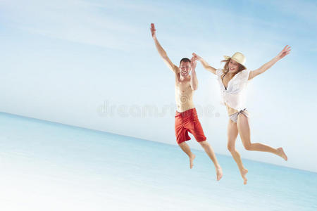 美丽的年轻夫妇在海滩上跳跃