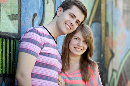 年轻夫妇在涂鸦背景附近接吻。