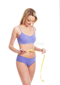 一个年轻的金发白种女人测量她的腰部