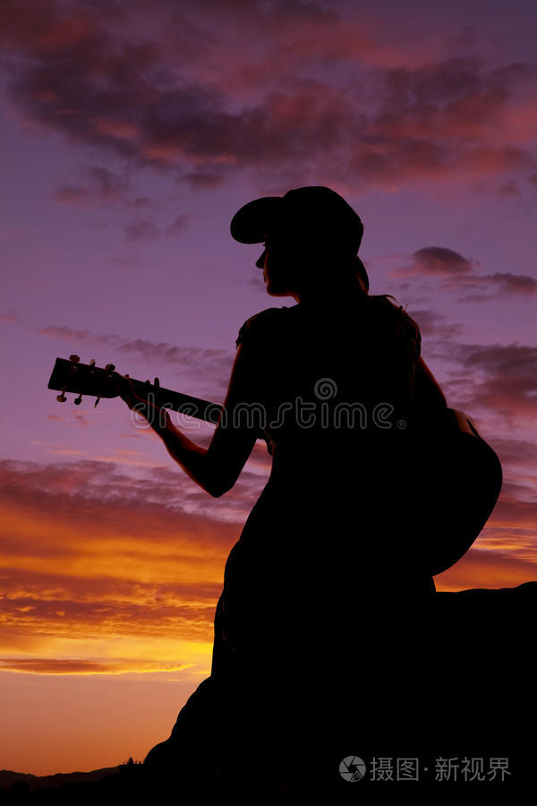 夕阳下坐着弹吉他的女人