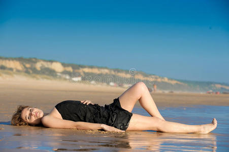 美丽的女人躺在沙滩上的圈套上