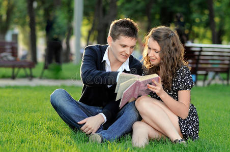 男孩和女孩坐在草地上看书图片