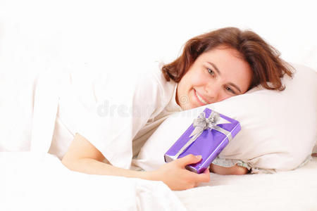 年轻漂亮的女人带着礼物在床上放松