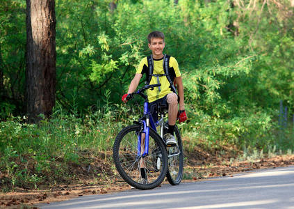 骑自行车在树林里旅行的少年