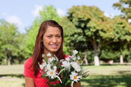 一个女人望着远方，手里拿着一束花