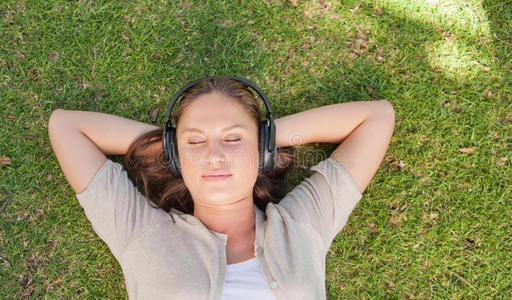躺在草坪上听音乐的放松的女人