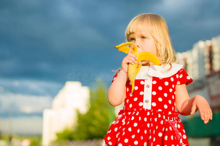 穿漂亮裙子的可爱女孩吃香蕉