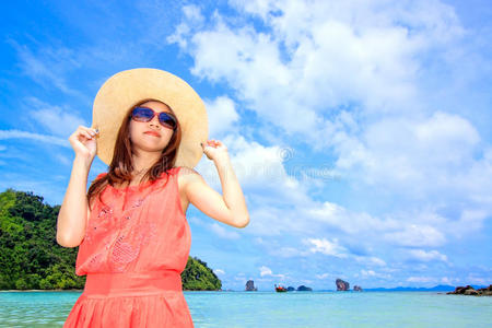 站在海滩上的一位身穿粉红色连衣裙的亚洲妇女