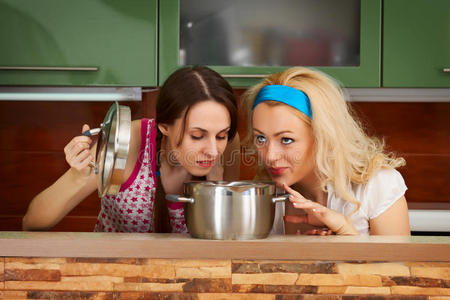 两个年轻女人端着一壶汤