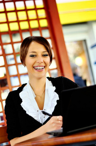 微笑的女人在咖啡馆用笔记本电脑