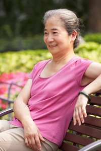 中国老太太在公园长凳上放松