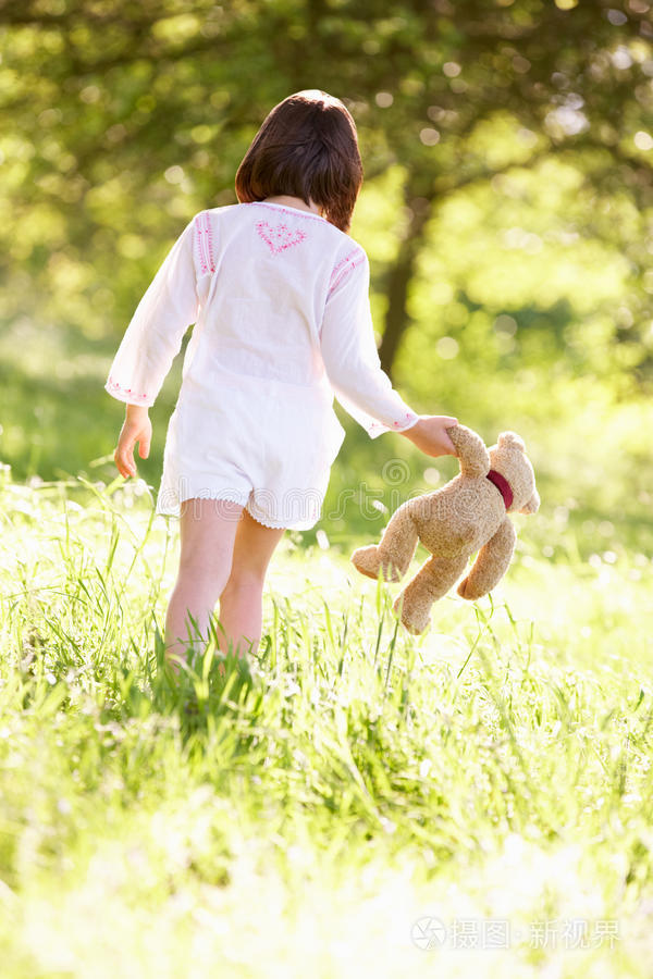 熊的小女孩蹒跚学步的小女孩抚摸着春花可爱的四岁女孩看着镜头婴儿