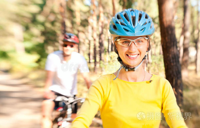 一对夫妇骑自行车在阳光明媚的森林里