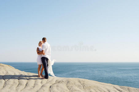 站在海边岩石上的年轻夫妇