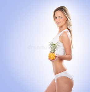 一个年轻的金发女人手里拿着一个新鲜的菠萝
