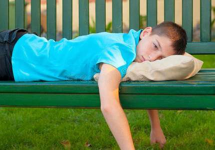 悲伤孤独的十几岁男孩躺在长凳上